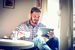 Mann am Tisch mit Tablet und Kaffee
